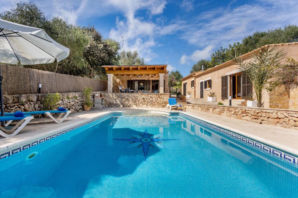 a pool with an umbrella and a house at Son Sec mit Pool und Wifi in Cala Santanyi