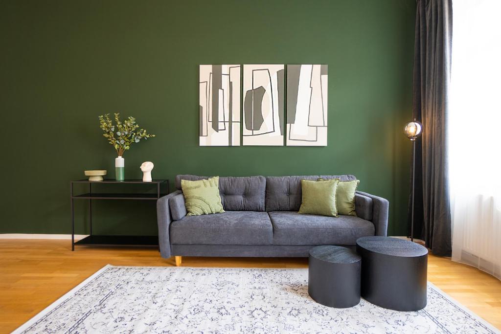 a living room with a gray couch and a green wall at Brand-new apartment with a breathtaking design located right near Belvedere Castle, 15 minutes from city centre in Vienna