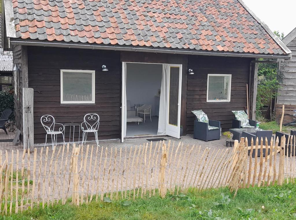 Casa negra con patio con sillas y mesa. en Cosy Cottage, 