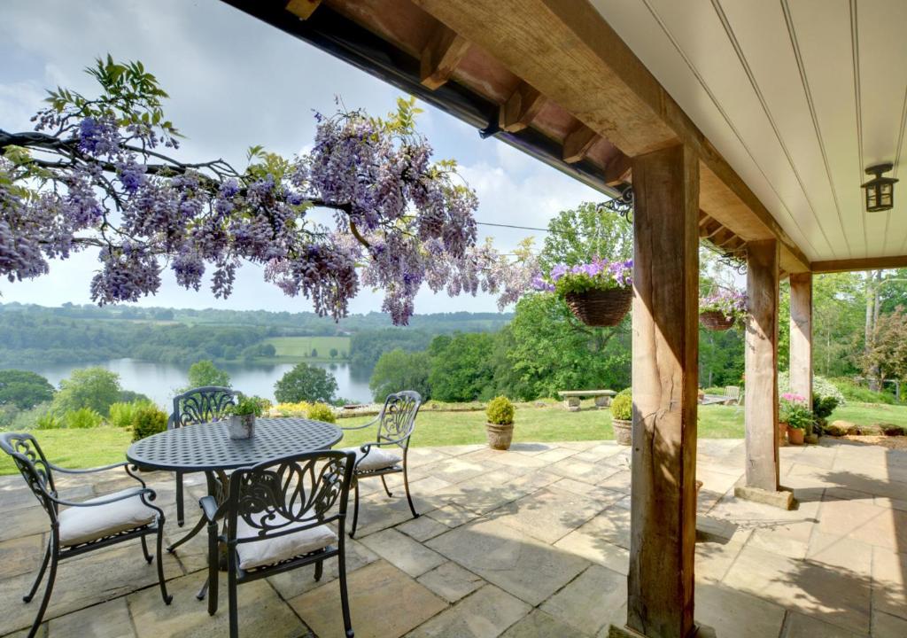 a patio with a table and chairs and a view of a lake at Bewl Water View in Ticehurst