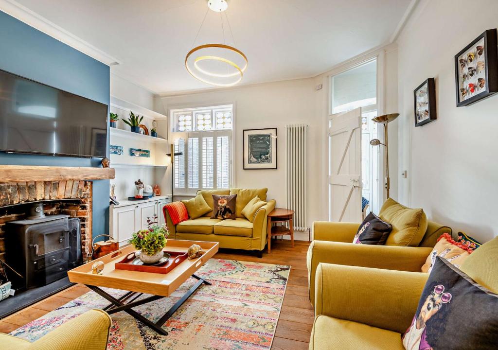 a living room with yellow furniture and a fireplace at Beachtown Cottage in Broadstairs