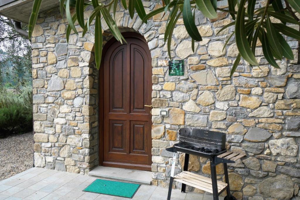 una casa in pietra con una porta in legno e una griglia di U Ciousu by Ligurian Life APPARTAMENTI IN AGRITURISMO a Vallebona