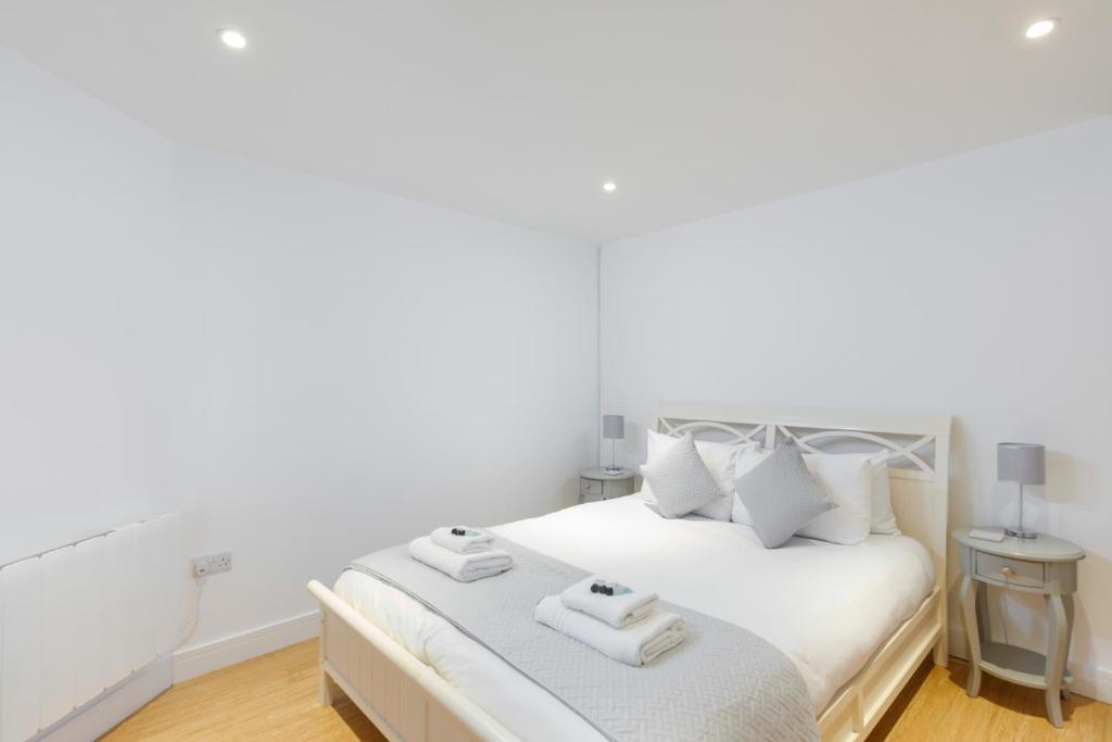 ein weißes Schlafzimmer mit einem Bett mit zwei Handtüchern darauf in der Unterkunft Central, Spacious 1 Bed- Hove in Brighton & Hove
