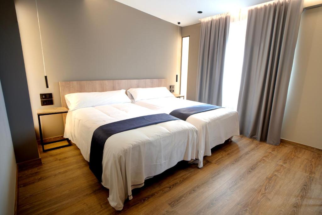 um quarto com uma cama grande com lençóis brancos e azuis em HOTEL RIO LEA 