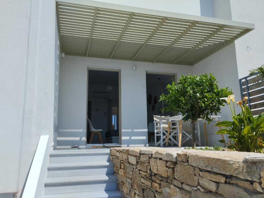 a white house with a porch with a wooden roof at Allegro suite in Tinos Town