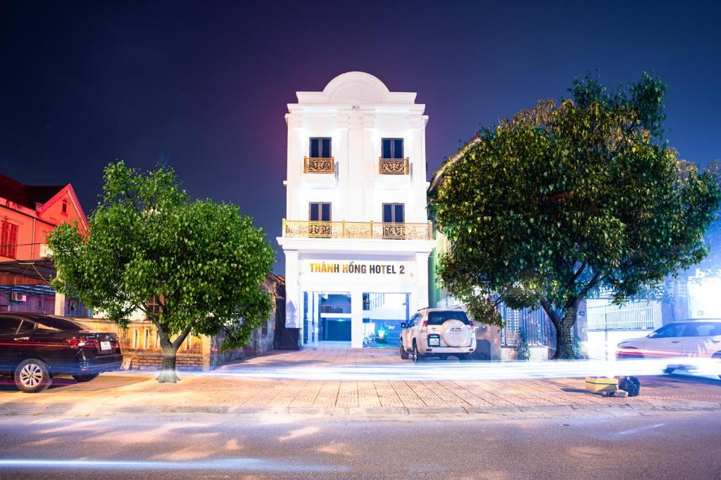 THÀNH HỒNG HOTEL في ها تينه: مبنى أبيض فيه سيارة متوقفة أمامه