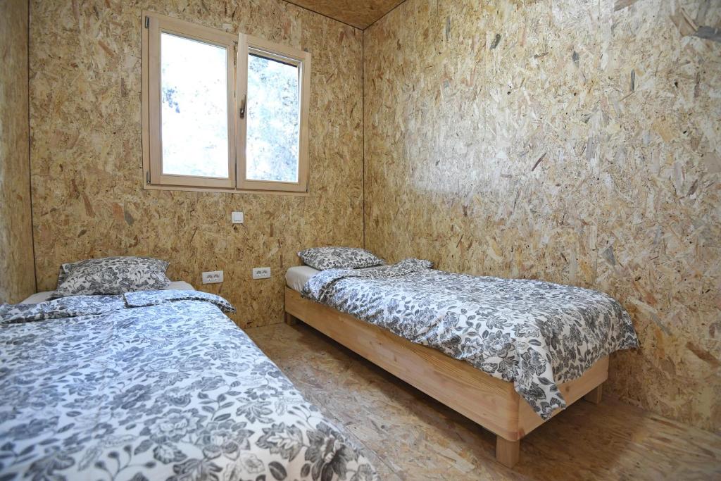 2 camas individuales en una habitación con ventana en TreeHouses Ljubač Glamping Robinson, en Ljubač