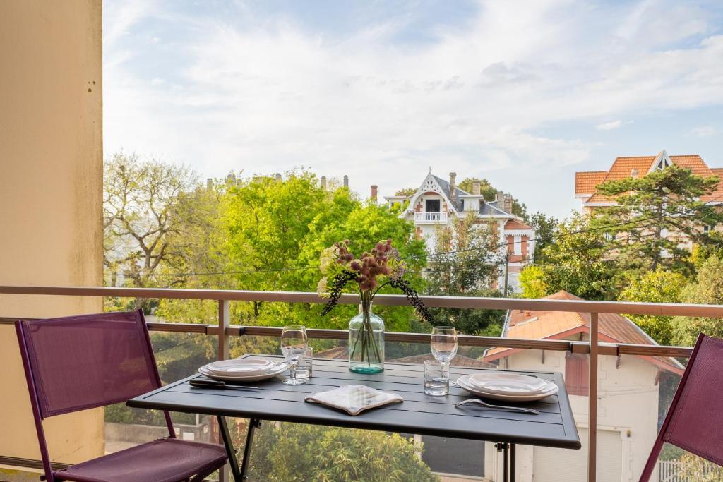a table with glasses and a vase on a balcony at Le Mesnil - 200m des plages in Arcachon