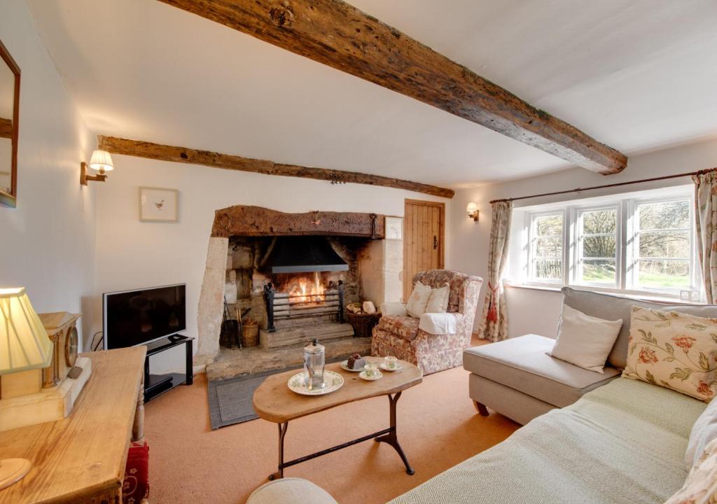 a living room with a couch and a fireplace at Carters Cottage in Slaughterford