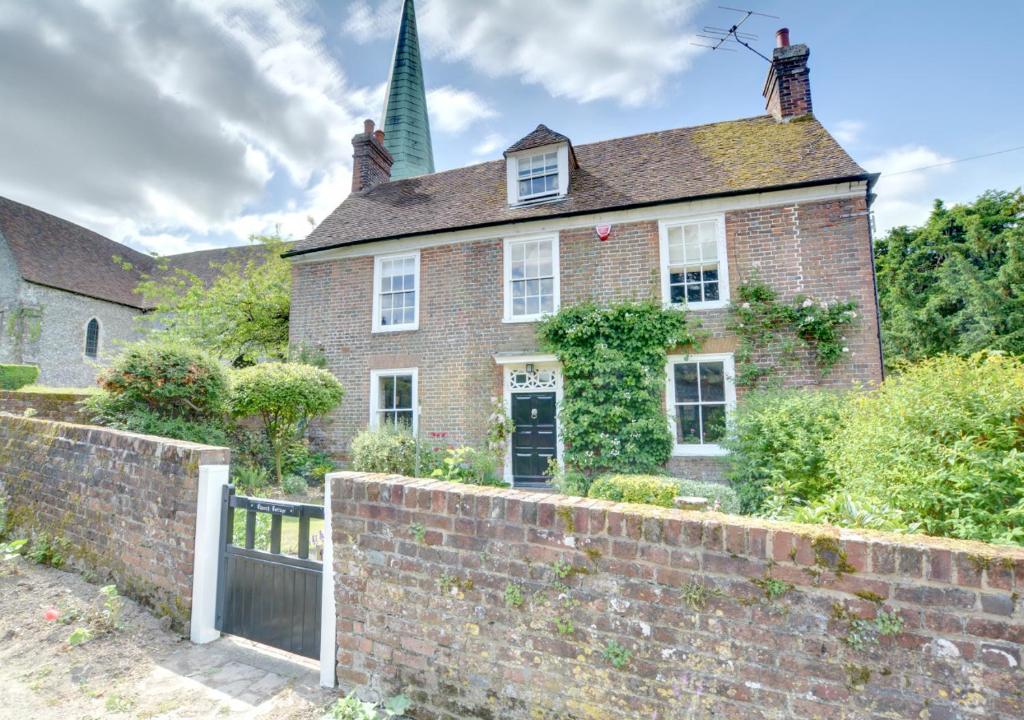 uma antiga casa de tijolos com uma parede de tijolos em Church Cottage em Barham