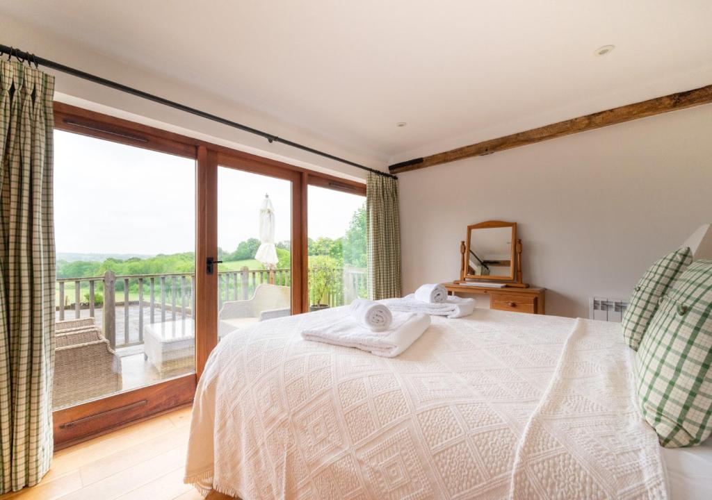 a bedroom with a bed and a large window at Dairy Cottage in Wadhurst