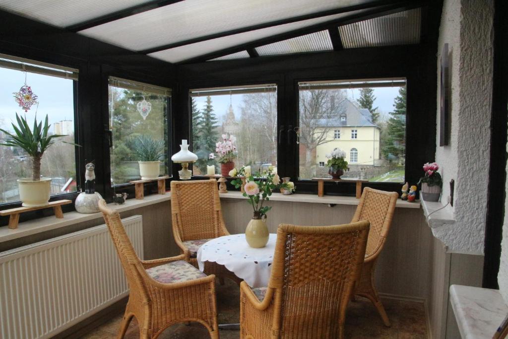 uma sala de jantar com mesa, cadeiras e janelas em Ferienwohnung Talblick em Annaberg-Buchholz