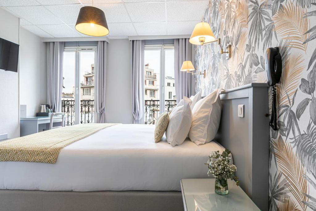 パリにあるホテル スプレンディドの大きなベッドとデスクが備わるホテルルームです。