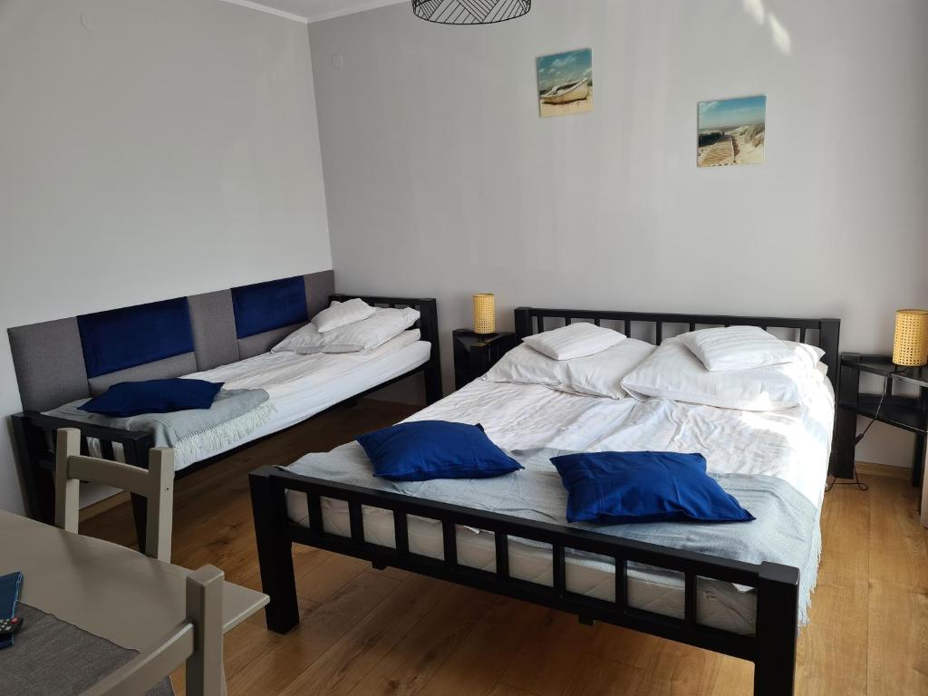 twee bedden in een kamer met blauwe kussens erop bij Przy porcie in Łeba