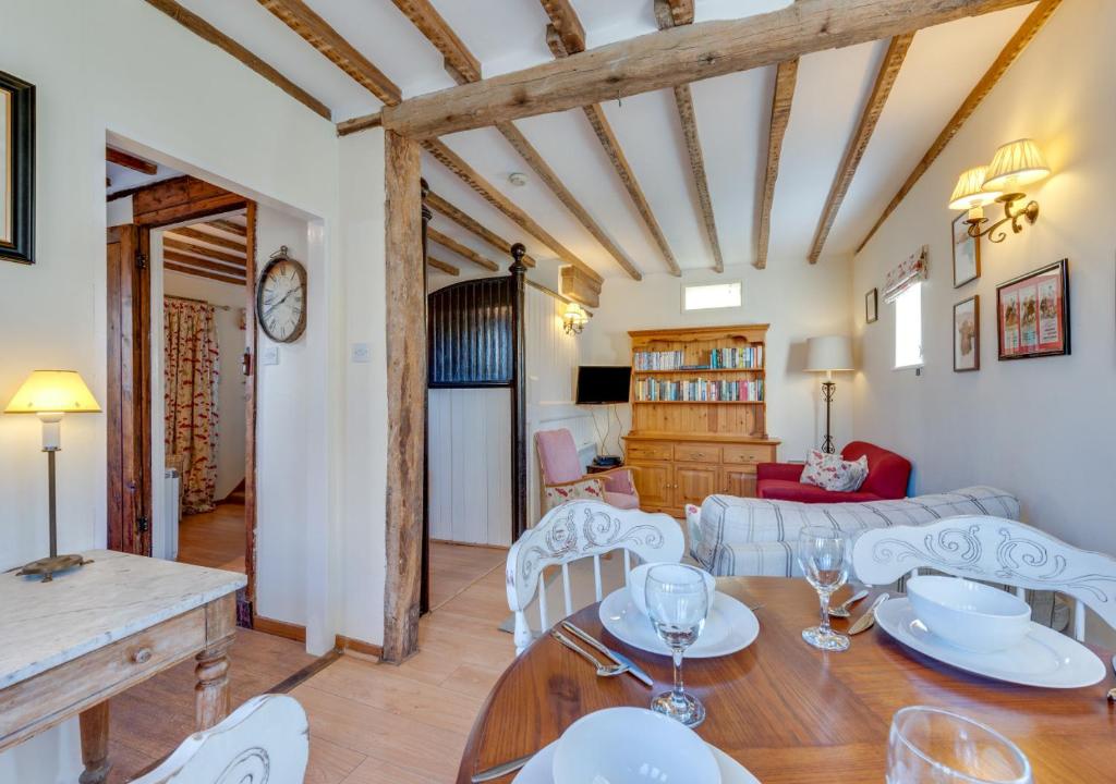 a dining room and living room with a table and chairs at Firs Coach House in Rolvenden