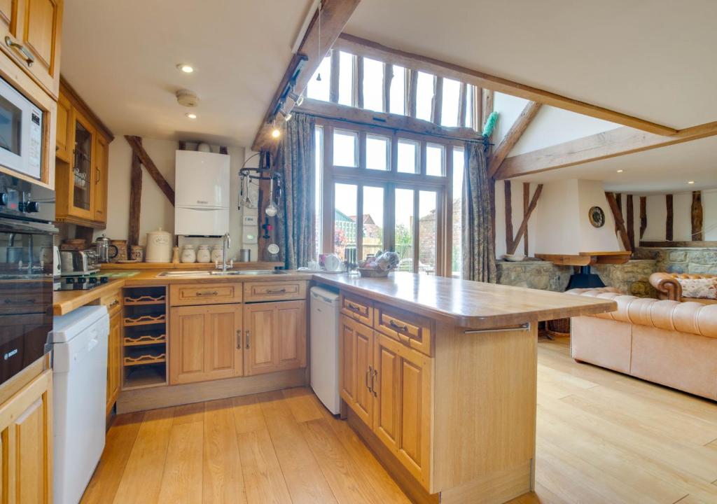 a large kitchen with wooden cabinets and a large window at Hartley Dyke Barn in Cranbrook