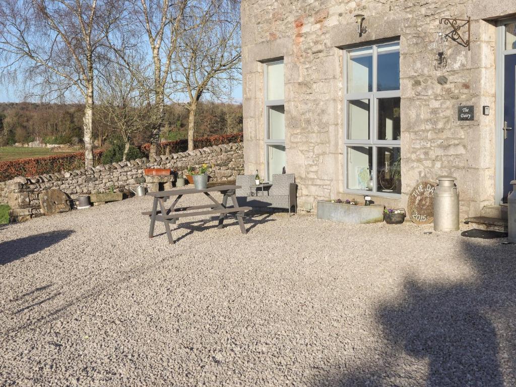 a patio with a bench and a stone building at The Dairy - Uk38043 in Beetham