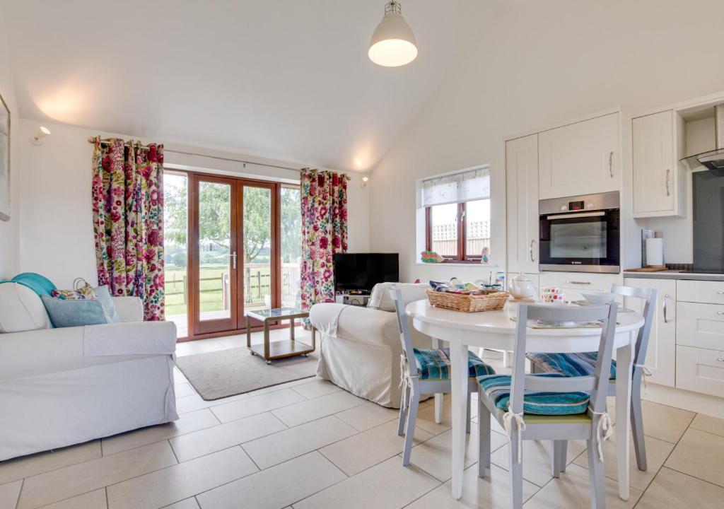 a kitchen and living room with a table and a couch at Hexden Lea in Rolvenden