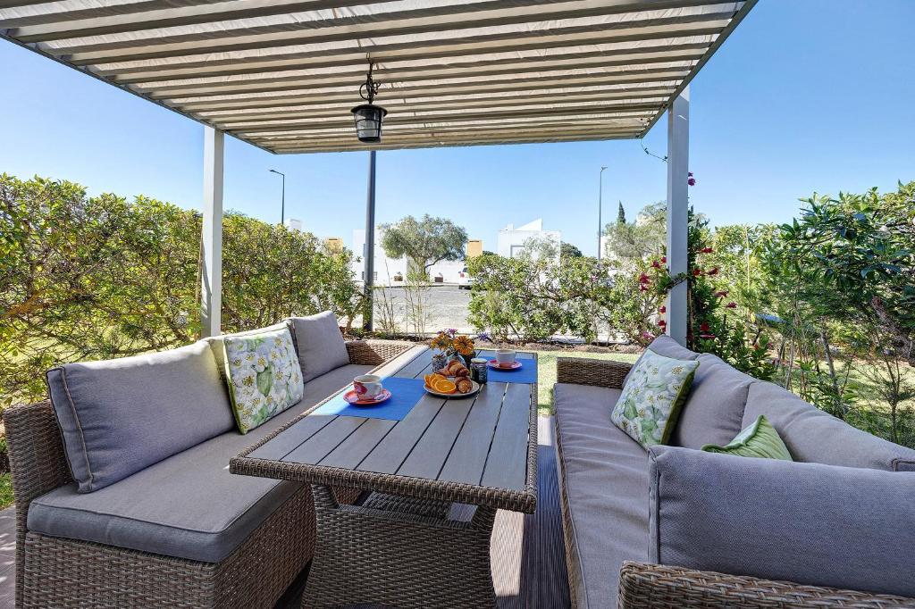 a patio with a wooden table and two couches at Villa Roxana in Porches
