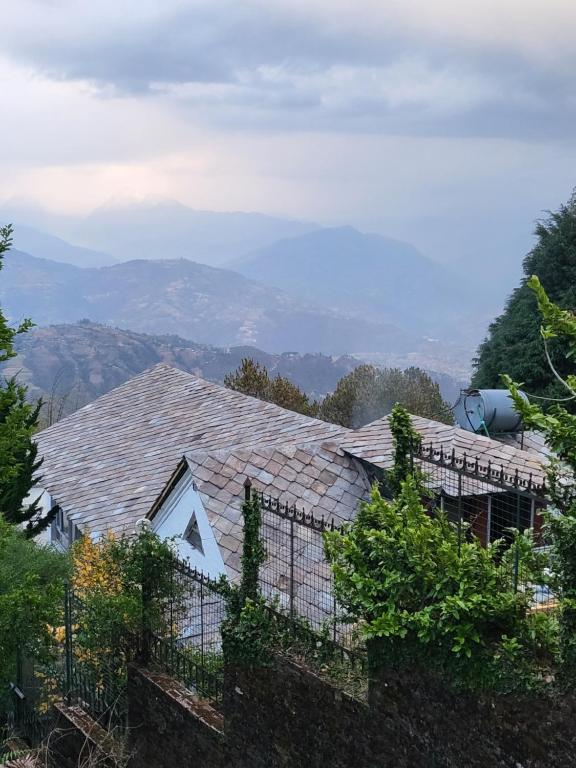 a house with a roof with mountains in the background at NALDUM VILLAGE RESORT By The Edge Nagarkot in Nagarkot