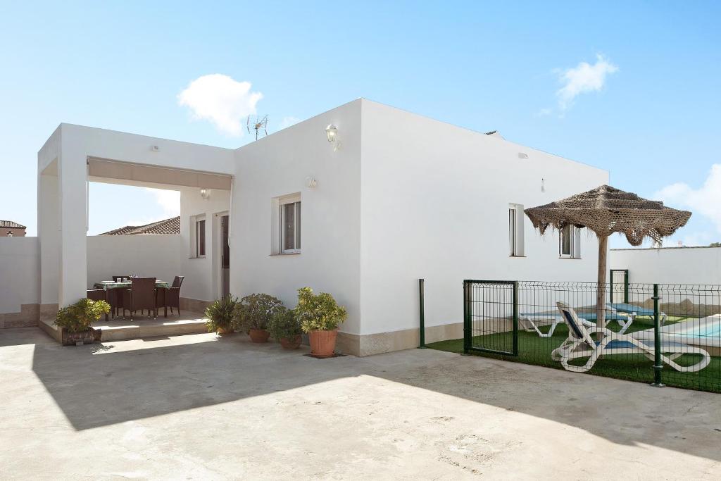ein weißes Haus mit einer Terrasse und einem Sonnenschirm in der Unterkunft Casa Josisa - Solo Familias in Conil de la Frontera