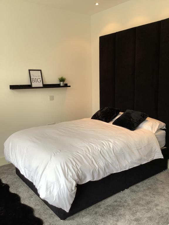 a bedroom with a large bed with a black headboard at The Secret Garden in Cheadle