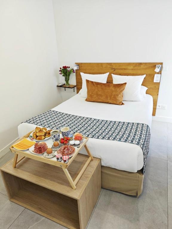 ein Hotelzimmer mit einem Bett und einem Tablett mit Essen in der Unterkunft HOTEL DES CALANQUES Port de Cassis in Cassis
