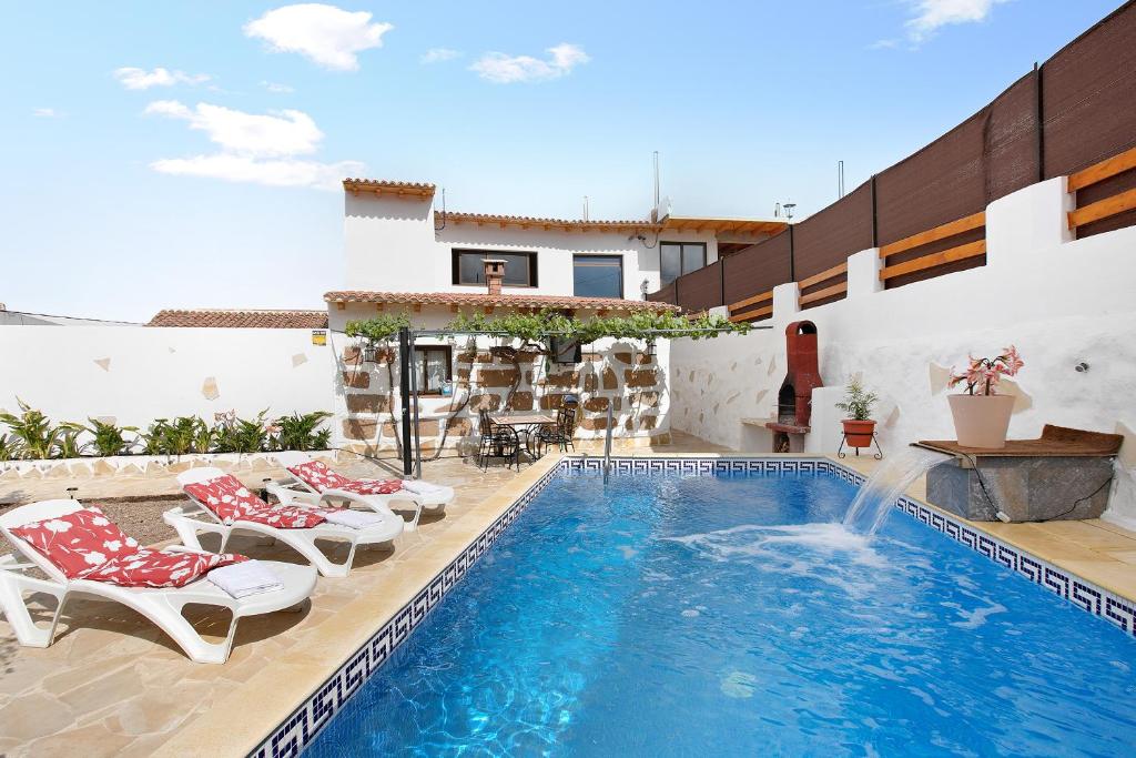 a swimming pool with chairs and a fountain in a house at Finca Keyfer in Vilaflor