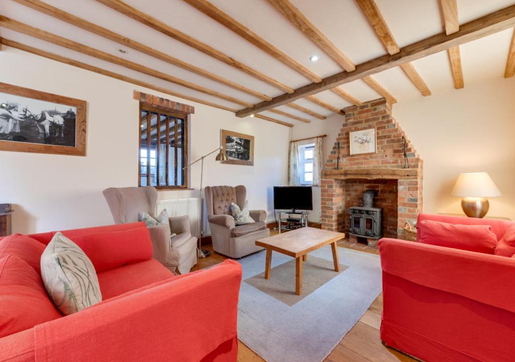 a living room with two red couches and a fireplace at Iden Green Farm Stables in Benenden