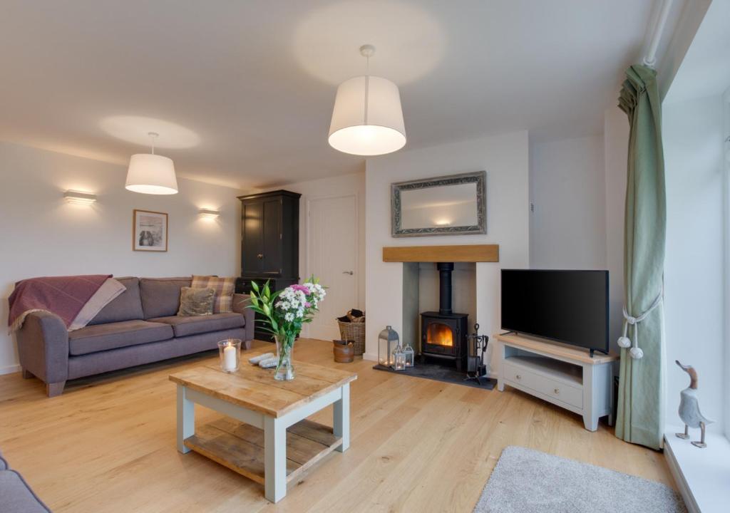 a living room with a couch and a fireplace at Little Orchard in Sedlescombe