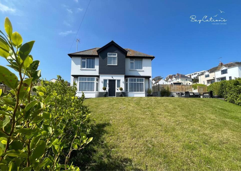 a black and white house on a green lawn at Stylish Brixham home, sleeps 7, parking & garden in Brixham