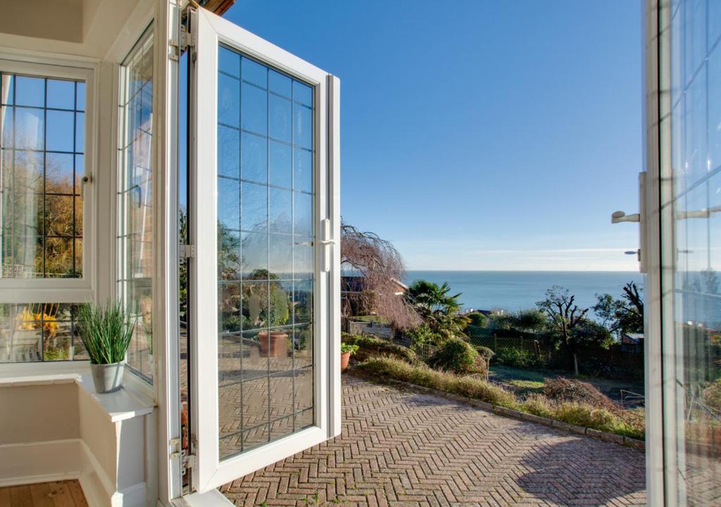 an open door to a balcony with a view of the ocean at Melbury Abbas in Sandgate