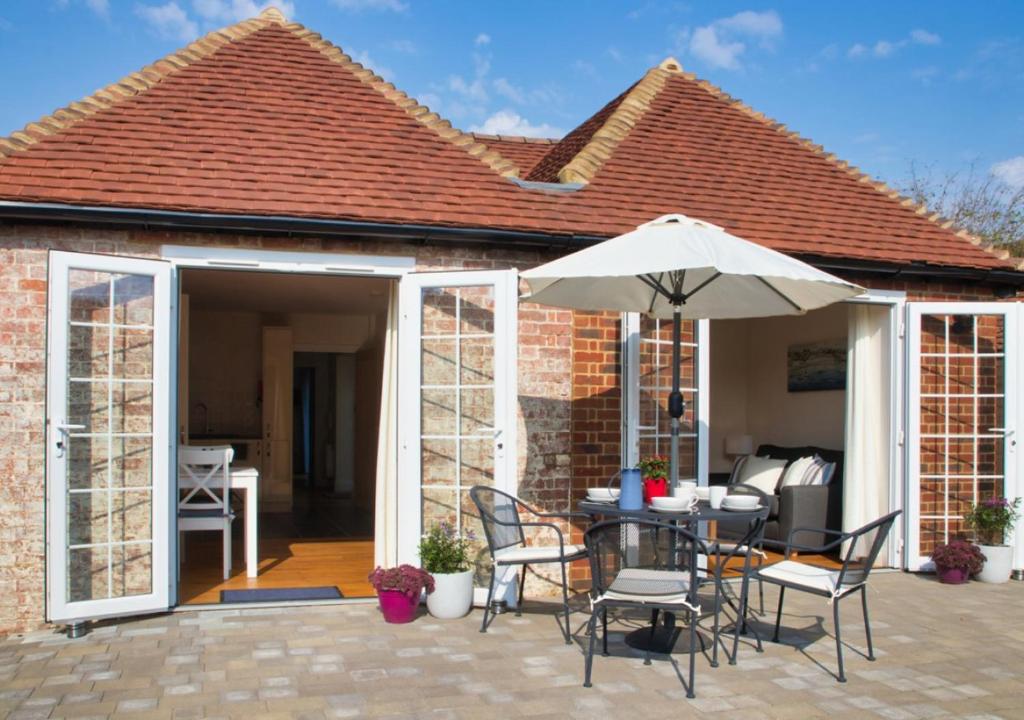 a patio with an umbrella and a table and chairs at Maple Cottage in Woodchurch