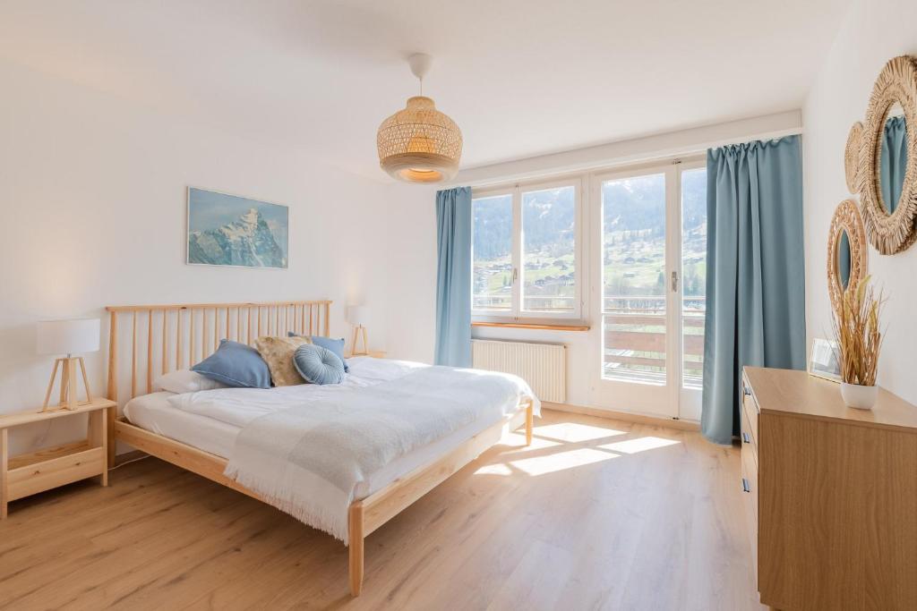 a bedroom with a bed and a large window at The Eiger Express Apartment - GRINDELHOMES in Grindelwald