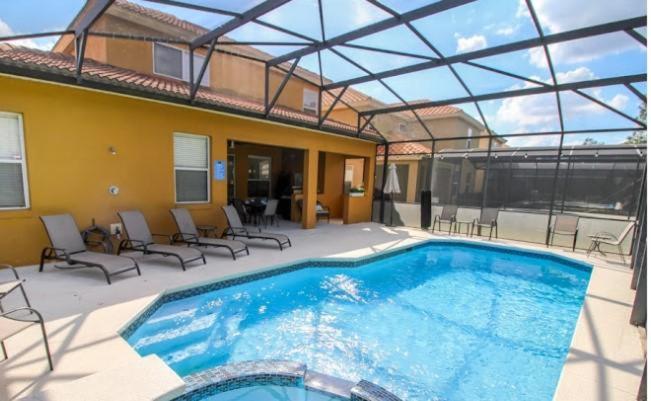 a large swimming pool with chairs and a house at Casa Amore at Ellis Exclusive Villas in Davenport