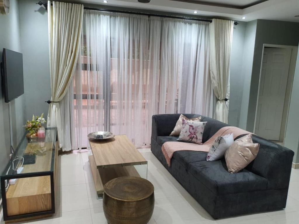 uma sala de estar com um sofá e uma mesa em Posh 3 bedroomed guesthouse in Hillside with pool - 2039 em Bulawayo