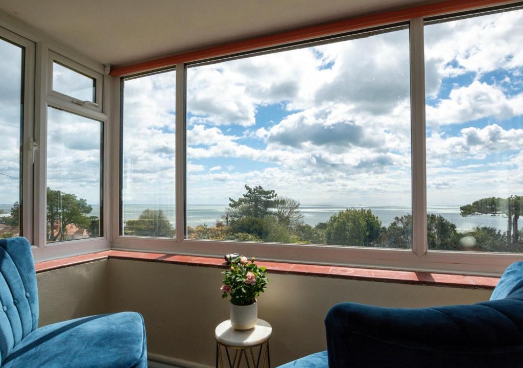 a room with two blue chairs and large windows at Rockmount in Saint Margaretʼs at Cliffe