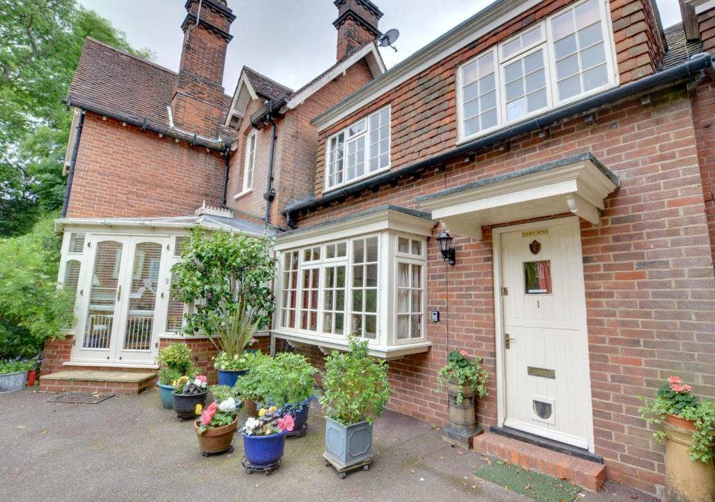 a brick house with potted plants in front of it at Stable Mews Cottage in Royal Tunbridge Wells