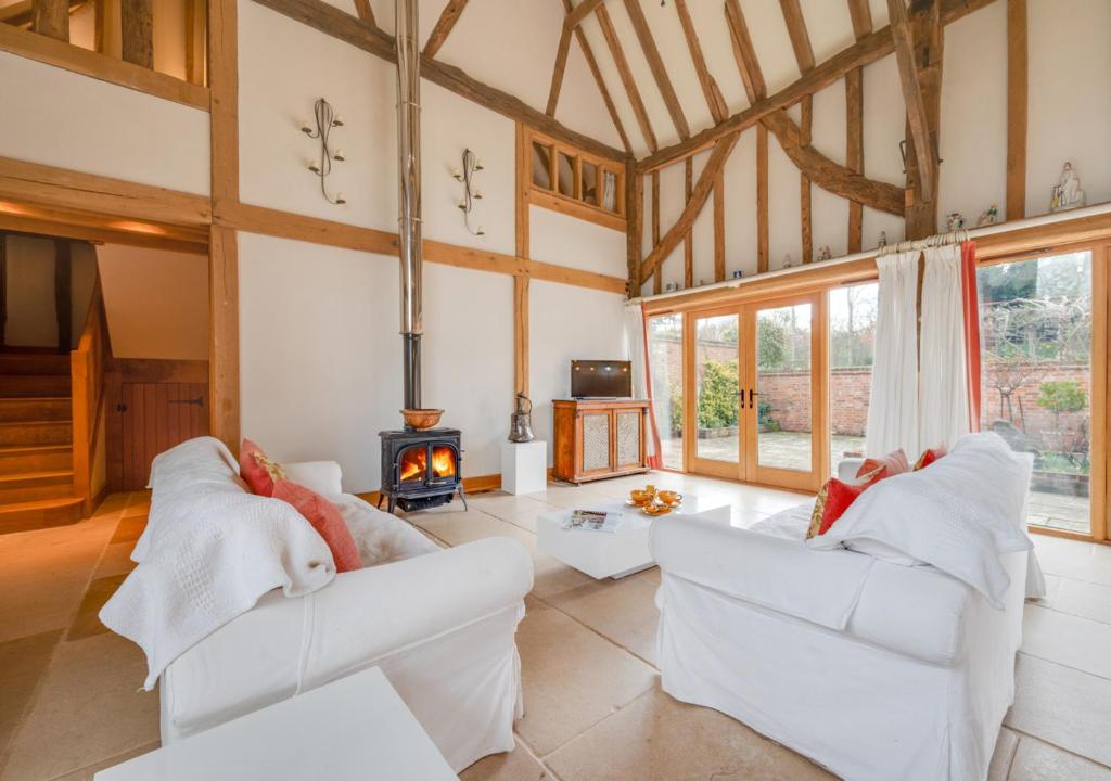 a living room with two white couches and a fireplace at Strawberry Hole Barn in Northiam