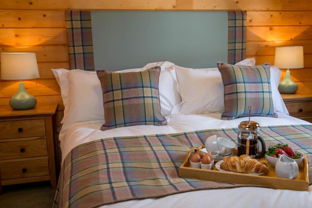 a bed with a tray of food on it at Stable Lodge in Drymen