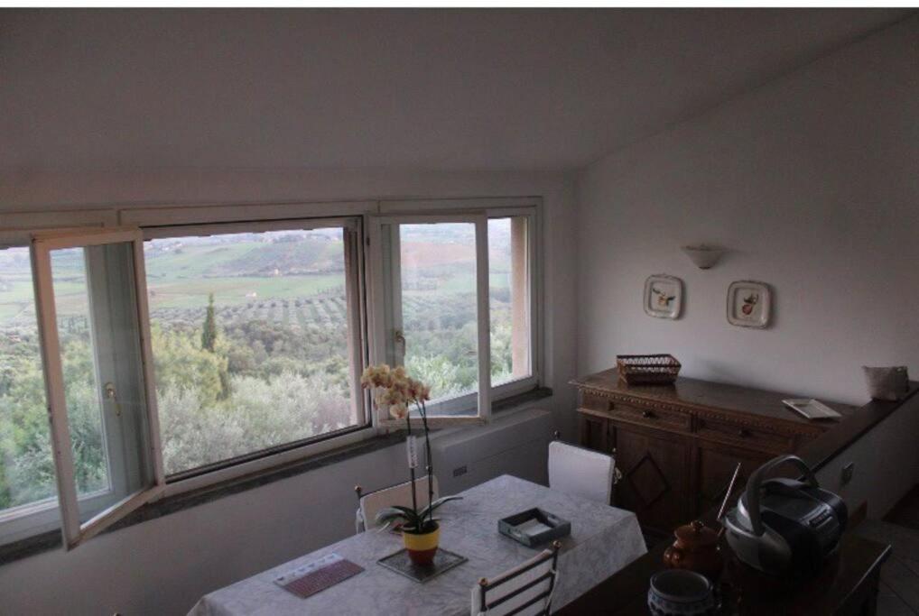 jadalnia ze stołem i dwoma dużymi oknami w obiekcie Affittasi a Capalbio per un minimo di 5 notti w mieście Capalbio