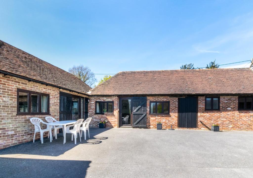 a patio with a table and chairs in front of a building at The Cowshed in Herstmonceux