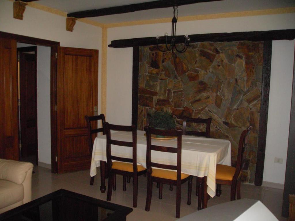 comedor con mesa, sillas y pared de piedra en Casa Gomera Mercedes, en San Sebastián de la Gomera