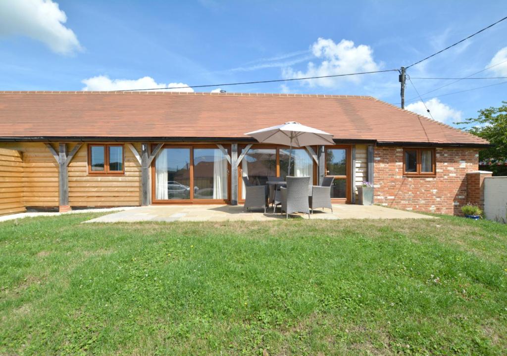 a house with an umbrella and chairs and a lawn at Waders in Beckley