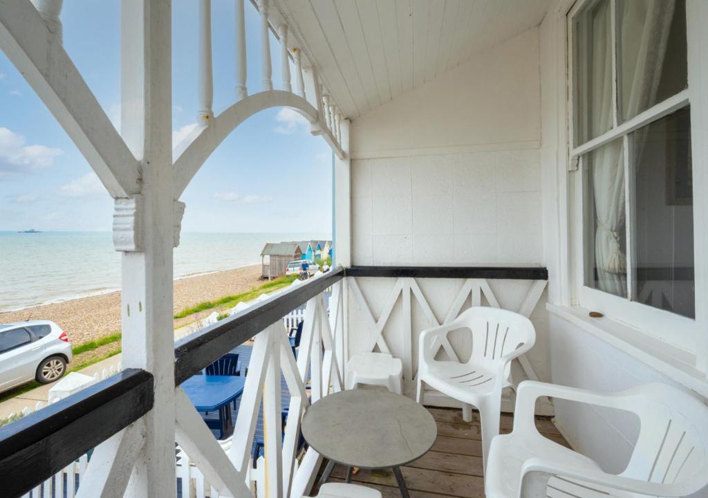 a balcony with white chairs and a table and the beach at Umballa in Herne Bay