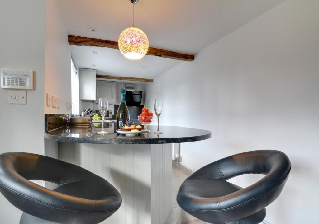 a kitchen with a counter with black leather stools at Well Cottage in Barham