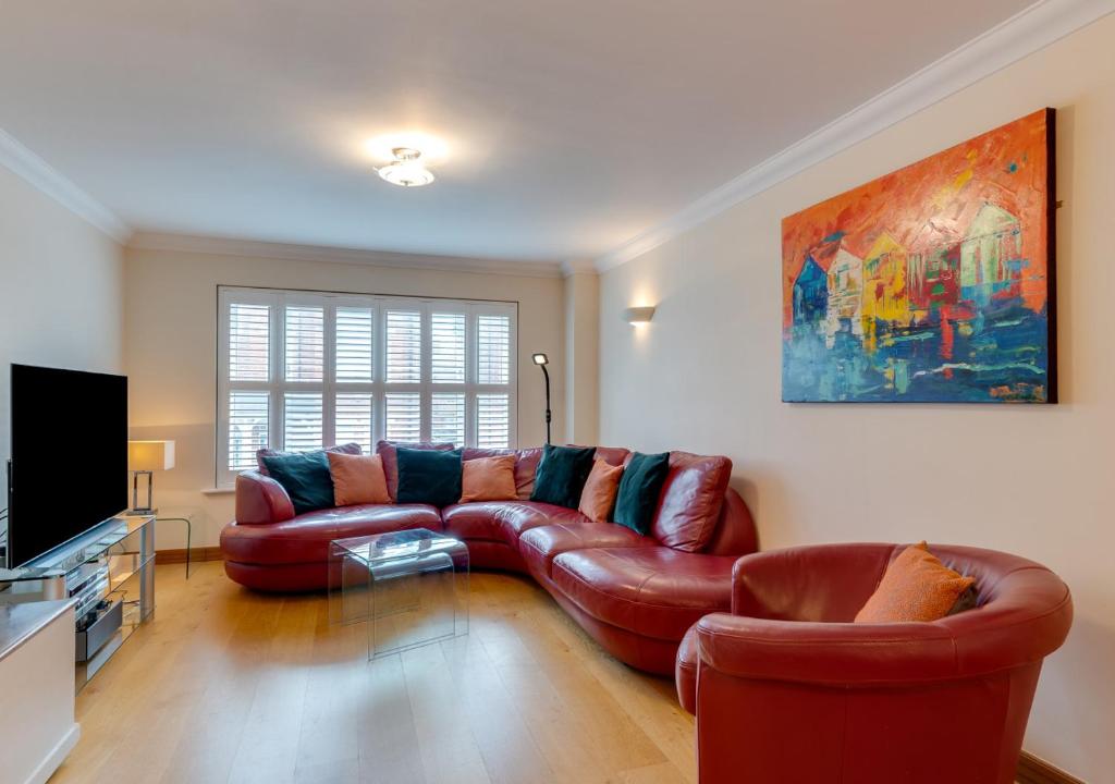 a living room with a leather couch and a television at York Mansions Apartment in Broadstairs