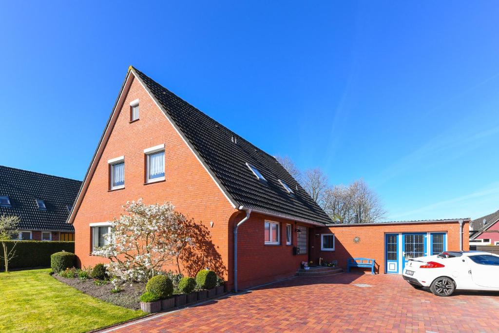 a red brick house with a car parked in the driveway at Ferienwohnung im Haus Leemreize in Blomberg