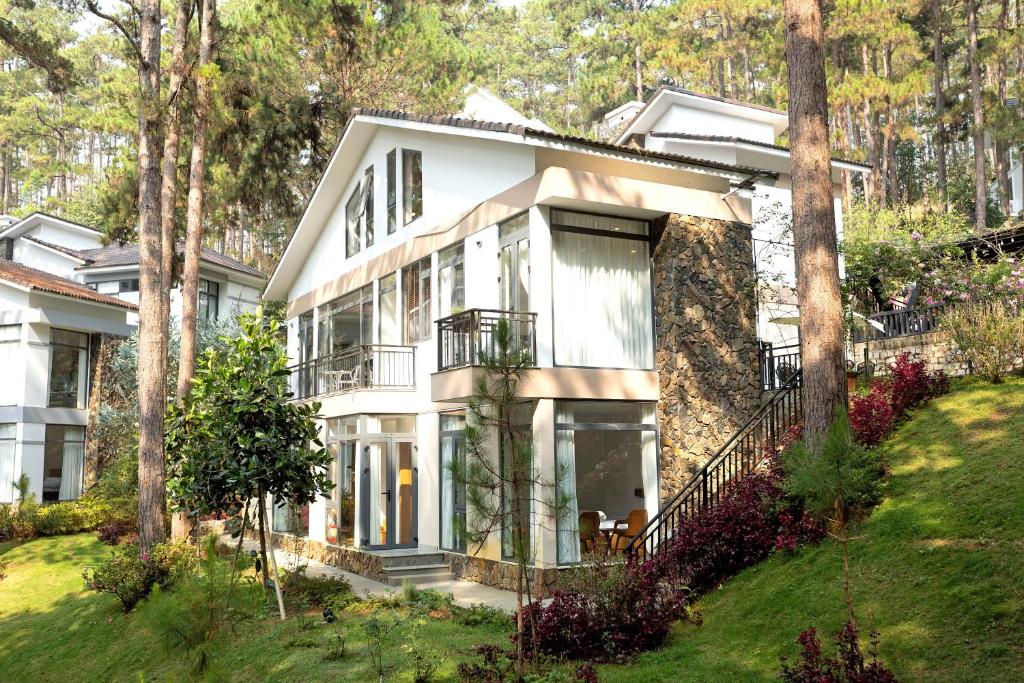a large white house with large windows and trees at Luxury 5 bedroom villa - Tuyen lam lake view in Xuan An