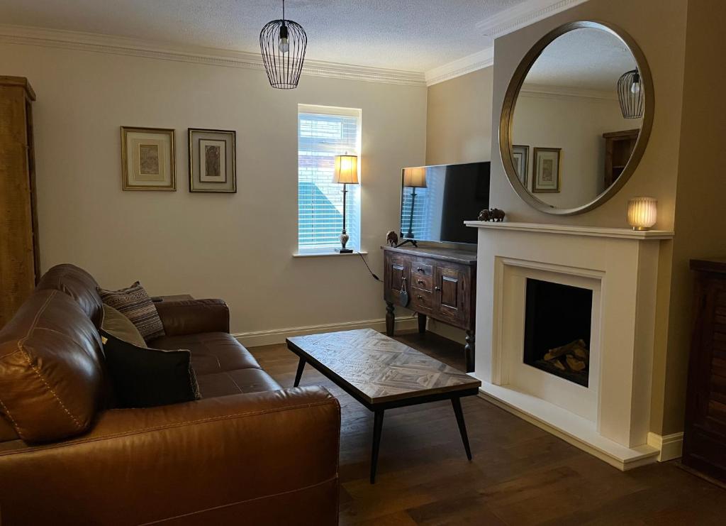 a living room with a couch and a mirror at Stunning Beverley Bungalow w Fireplace, private parking, and garden in Beverley